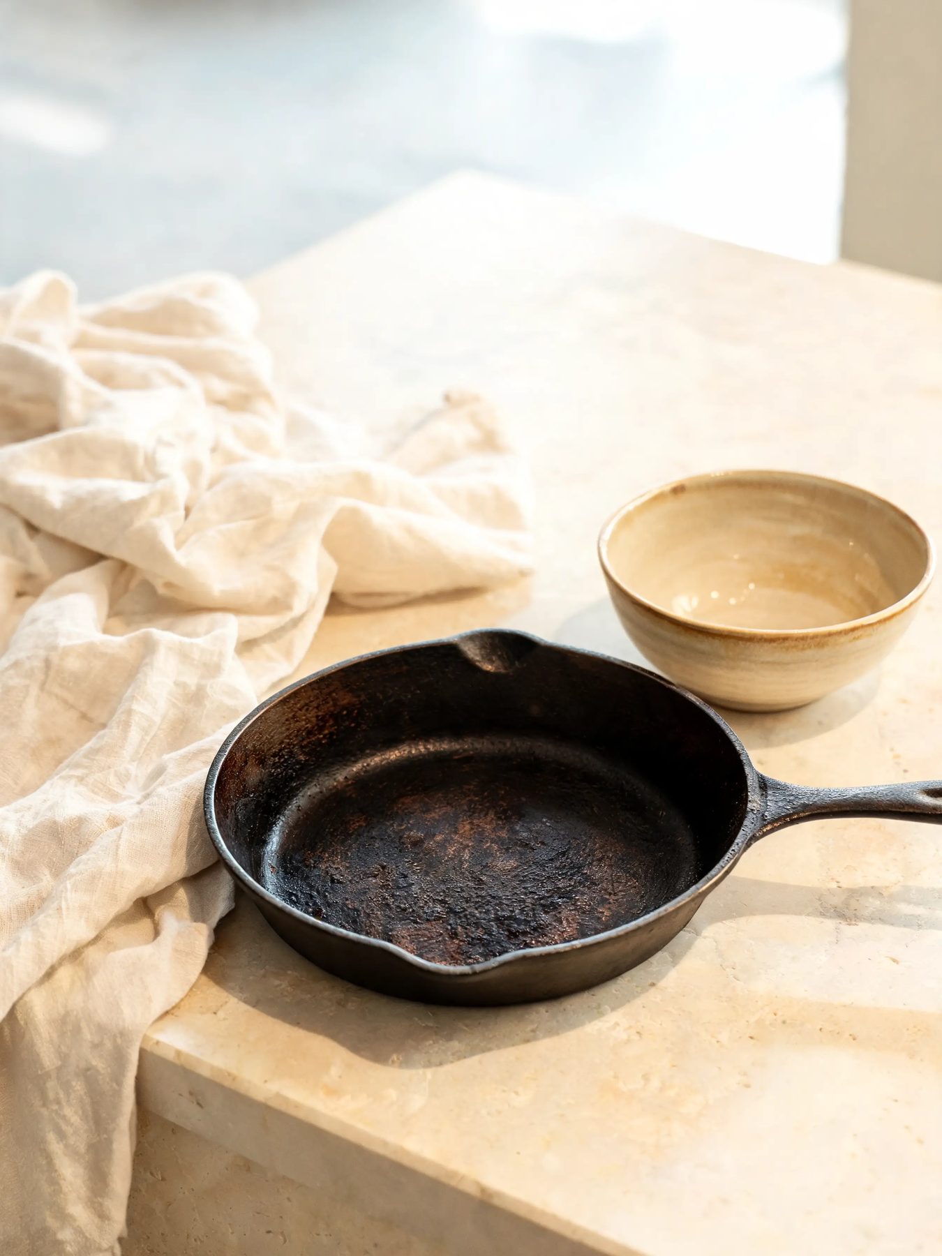 Seasoned skillet and glazed stoneware bowl on a limestone counter